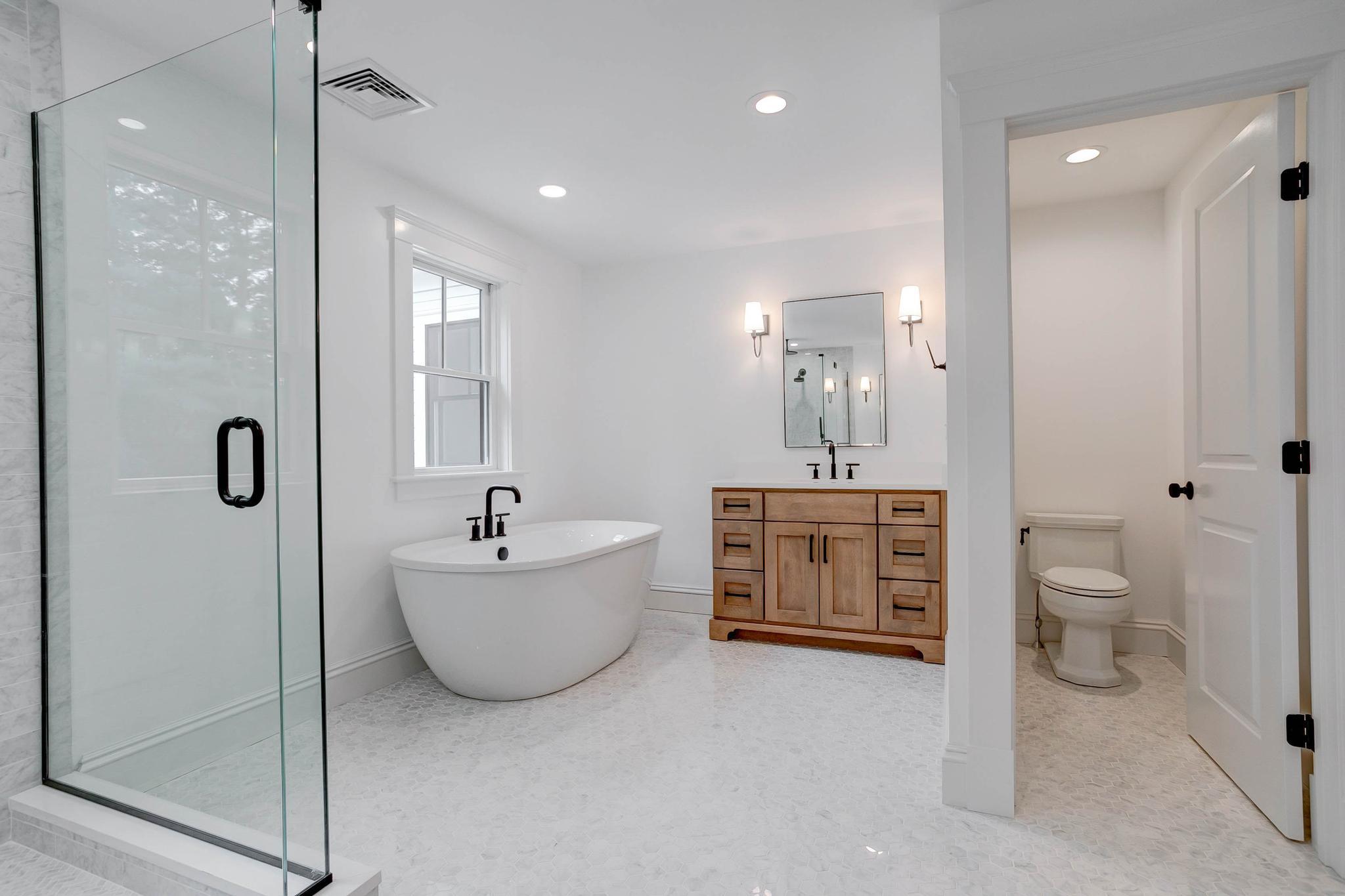 Modern bathroom with a glass shower, freestanding bathtub, wooden vanity with double sinks, wall-mounted lights, and a separate toilet area—perfect for special projects or unique design needs. Modern bathroom with a glass shower, freestanding bathtub, wooden vanity with double sinks, wall-mounted lights, and a separate toilet area—perfect for special projects or unique design needs.
